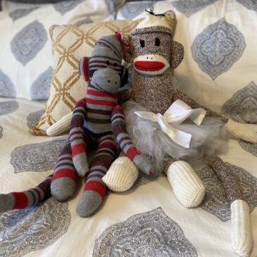 Two sock monkeys seated on a bed